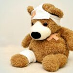 A brown teddy bear with bandages, depicting a playful take on injury recovery in a minimalist setting.